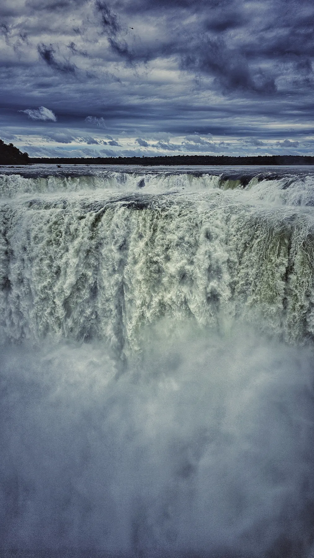 Ściana wody wodospadów Iguaçu pod ciemnymi chmurami.